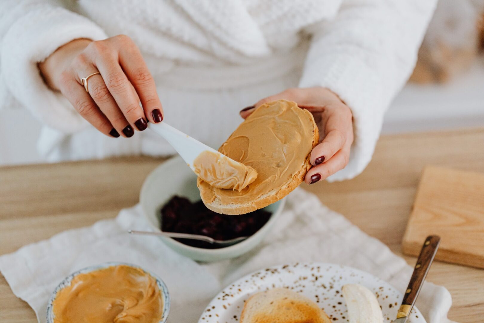 a woman applying peanut butter on a toast